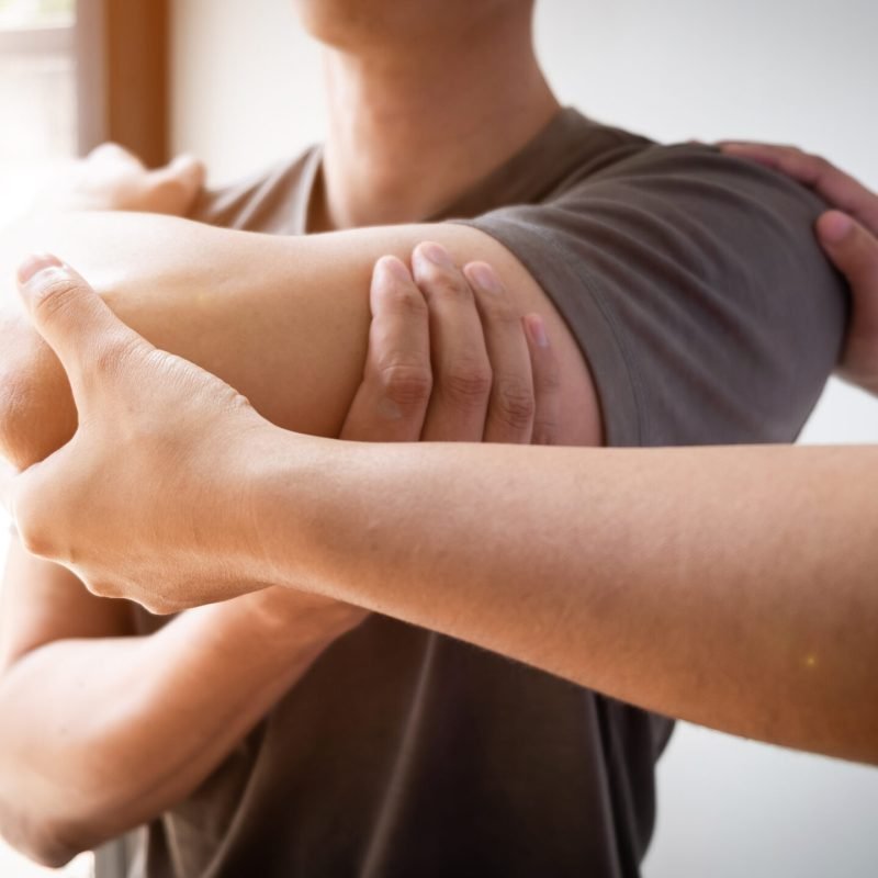 Therapist treating a male injured by rotator cuff stretching met